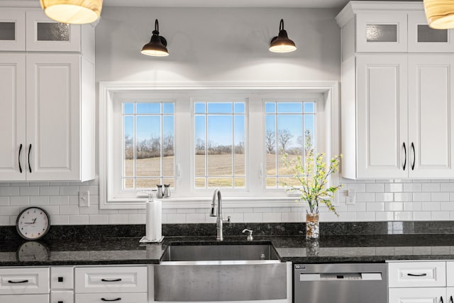 kitchen with stainless steel dishwasher, decorative backsplash, a sink, and white cabinets