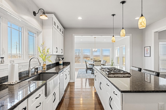 kitchen with plenty of natural light, dishwashing machine, dark wood-style floors, stainless steel gas stovetop, and a sink