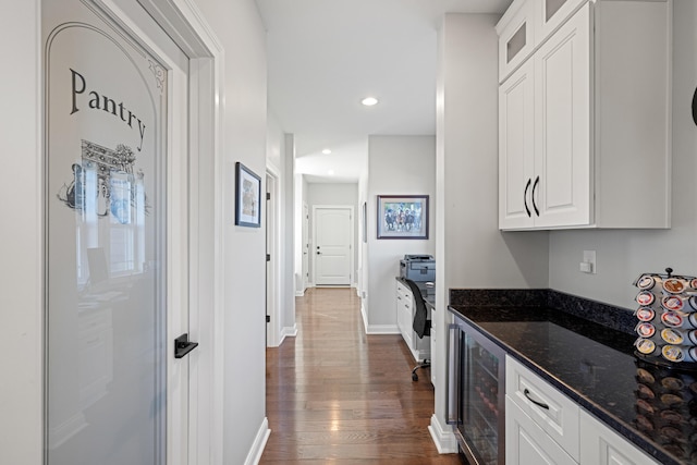 interior space featuring beverage cooler, white cabinetry, dark wood-style floors, dark stone countertops, and glass insert cabinets