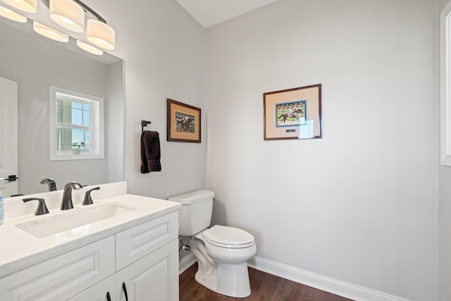 bathroom featuring toilet, baseboards, wood finished floors, and vanity