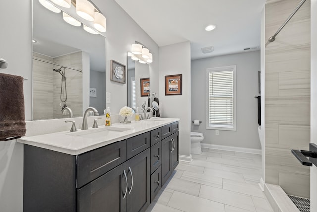 full bath with tiled shower, a sink, baseboards, and double vanity