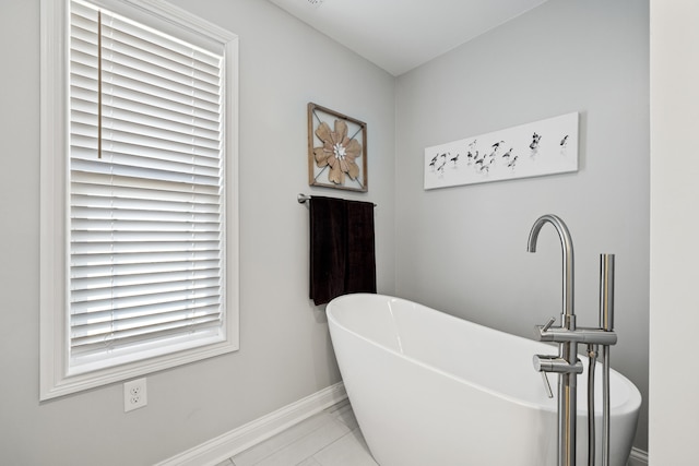 full bath featuring a freestanding bath and baseboards