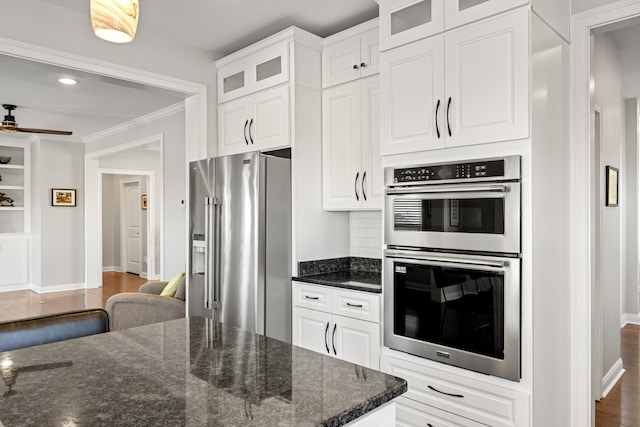 kitchen featuring dark wood-style floors, appliances with stainless steel finishes, white cabinetry, and crown molding