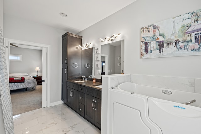 bathroom with double vanity, connected bathroom, a bath, marble finish floor, and a sink