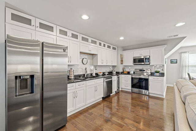 kitchen featuring appliances with stainless steel finishes, dark countertops, a sink, and visible vents