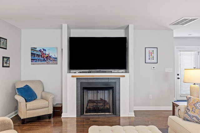 living area featuring baseboards, a fireplace, visible vents, and wood finished floors