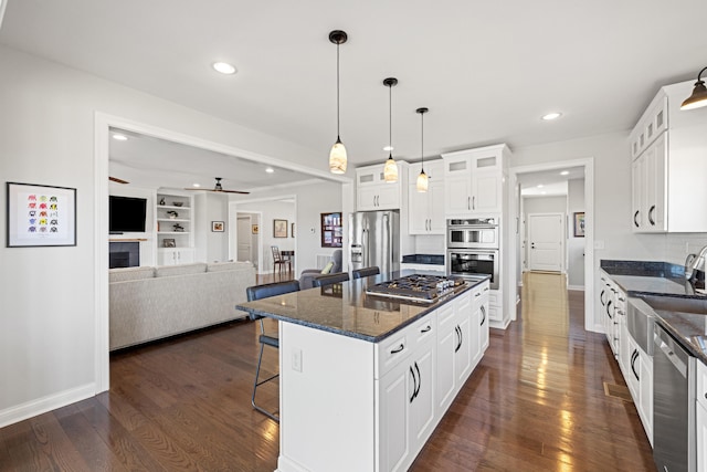 kitchen with dark wood-style flooring, a kitchen island, white cabinets, a kitchen breakfast bar, and appliances with stainless steel finishes