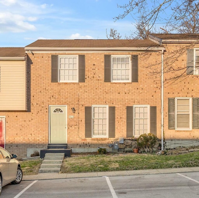 townhome / multi-family property featuring entry steps, uncovered parking, and brick siding