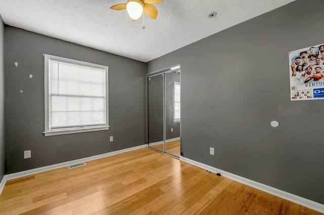 unfurnished bedroom featuring light wood-style floors, multiple windows, visible vents, and baseboards