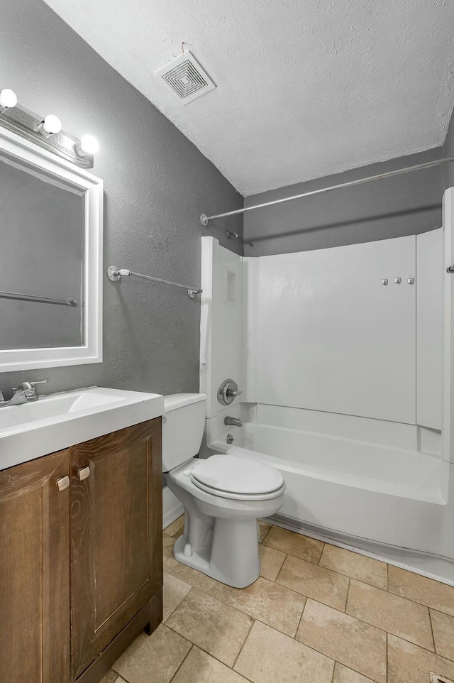 bathroom with a textured ceiling, a textured wall, toilet, and visible vents