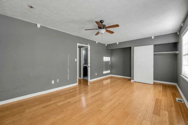 unfurnished bedroom with baseboards, visible vents, a textured ceiling, and light wood finished floors