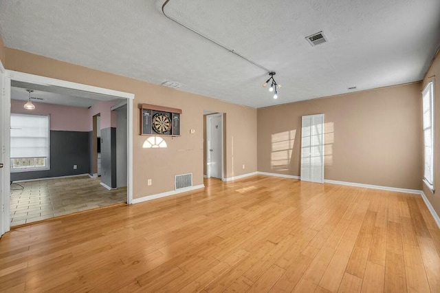 empty room featuring light wood-style floors, visible vents, and baseboards