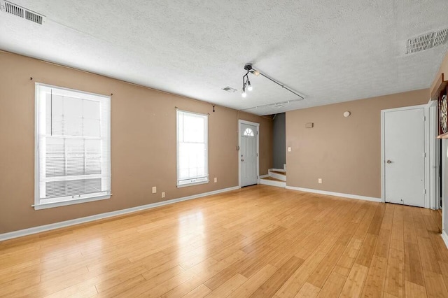 spare room featuring visible vents, a textured ceiling, and light wood-style flooring