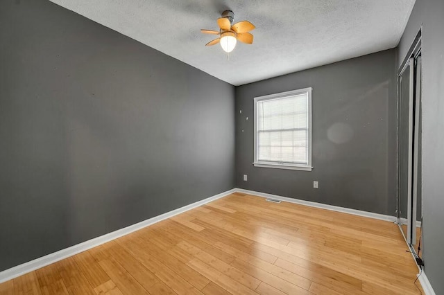 unfurnished room featuring visible vents, baseboards, ceiling fan, a textured ceiling, and light wood-style floors