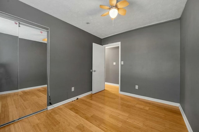 unfurnished bedroom with light wood-style flooring, baseboards, ceiling fan, and a closet