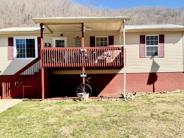 back of property featuring a deck, metal roof, a yard, and stairway