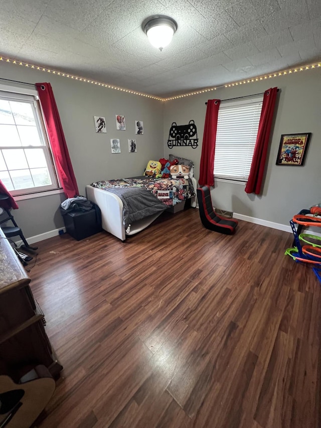 bedroom featuring dark wood-style flooring, a textured ceiling, and baseboards