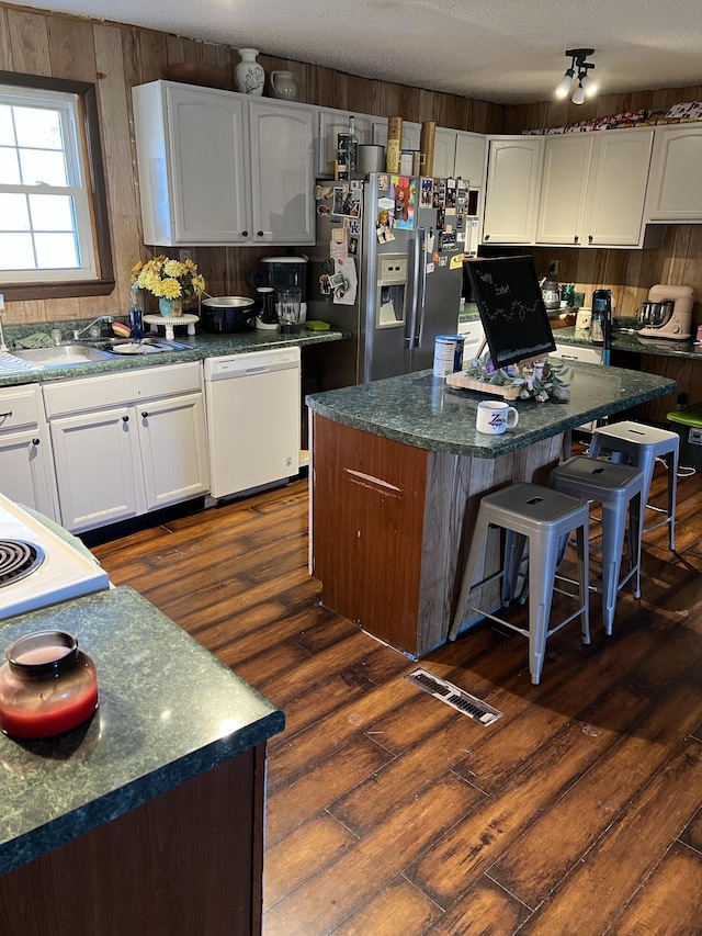 kitchen with white cabinets, dishwasher, stainless steel fridge with ice dispenser, a center island, and a sink