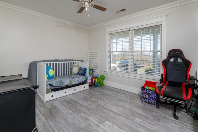 bedroom with ceiling fan, wood finished floors, visible vents, baseboards, and ornamental molding