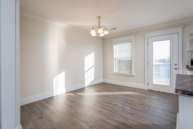 empty room with crown molding, a notable chandelier, visible vents, wood finished floors, and baseboards