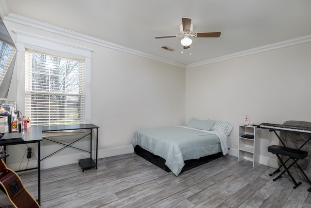 bedroom with wood finished floors, a ceiling fan, visible vents, baseboards, and ornamental molding