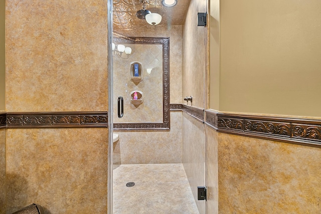 bathroom featuring a wainscoted wall and a shower stall