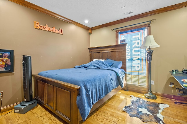 bedroom with visible vents, light wood-style flooring, ornamental molding, a textured ceiling, and baseboards