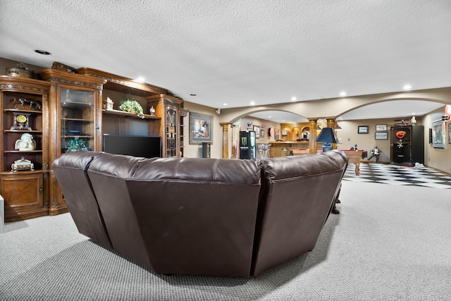 living area featuring arched walkways, a textured ceiling, light carpet, and recessed lighting