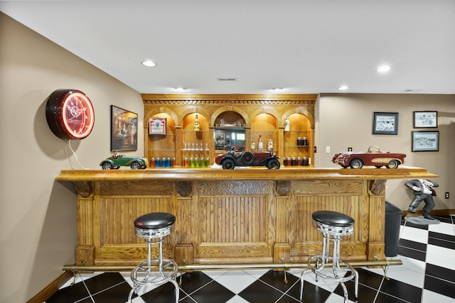 bar featuring baseboards, a bar, recessed lighting, and tile patterned floors