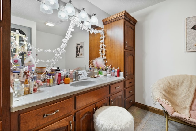 bathroom with tile patterned flooring, baseboards, vanity, and a textured ceiling