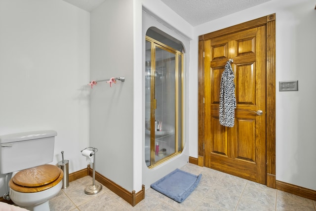 bathroom featuring tile patterned floors, a shower stall, toilet, and baseboards