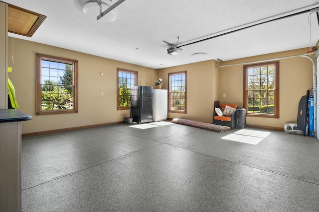 garage with a garage door opener, freestanding refrigerator, and baseboards