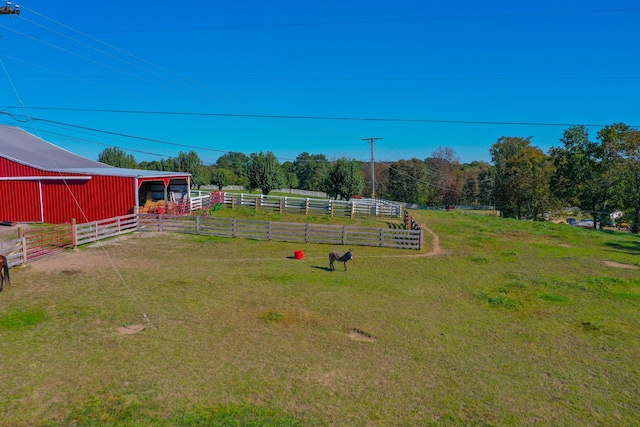 view of yard featuring a rural view, fence, an outbuilding, and an outdoor structure