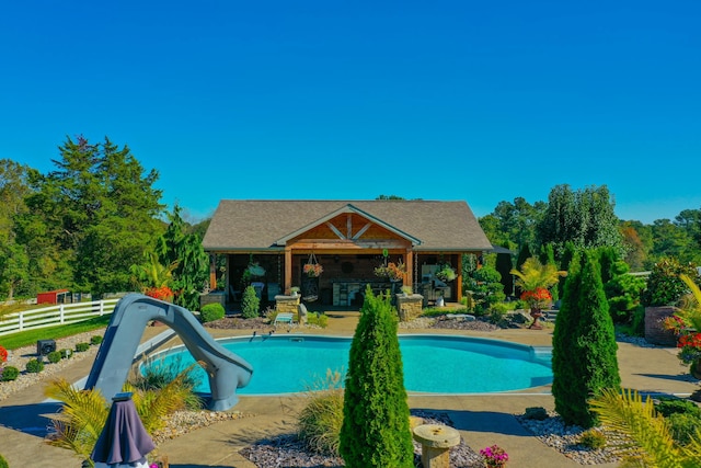 pool with a water slide, an outdoor bar, and fence