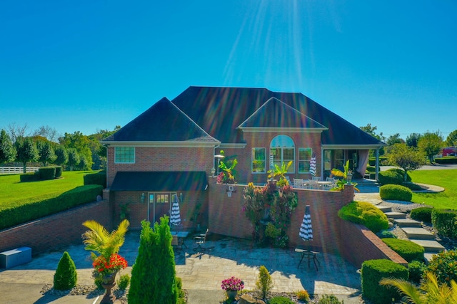 view of front of house featuring a patio area, a front lawn, and brick siding