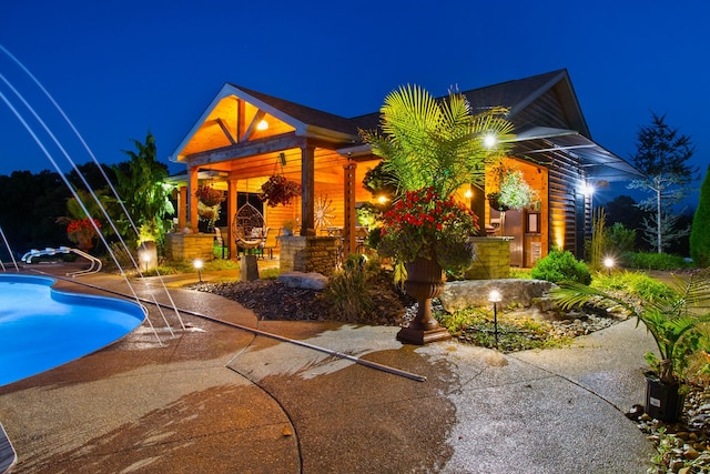 pool at twilight with a patio area and an outdoor pool