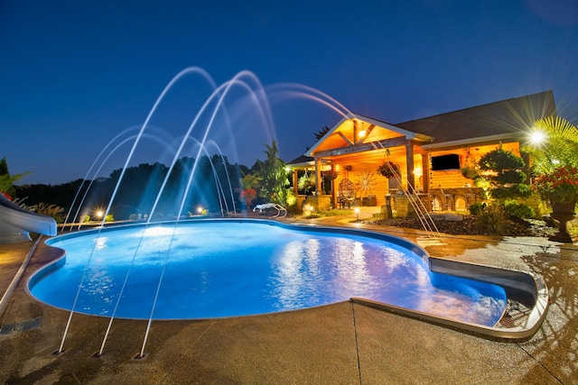 pool at twilight with a patio, a water slide, and an outdoor pool