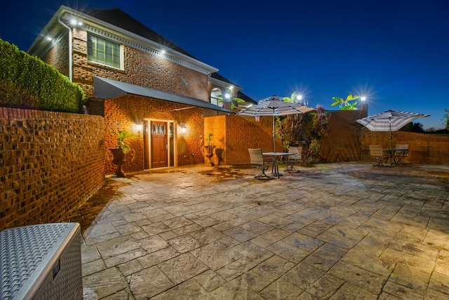 back of house at twilight with a patio area, a fenced backyard, and brick siding