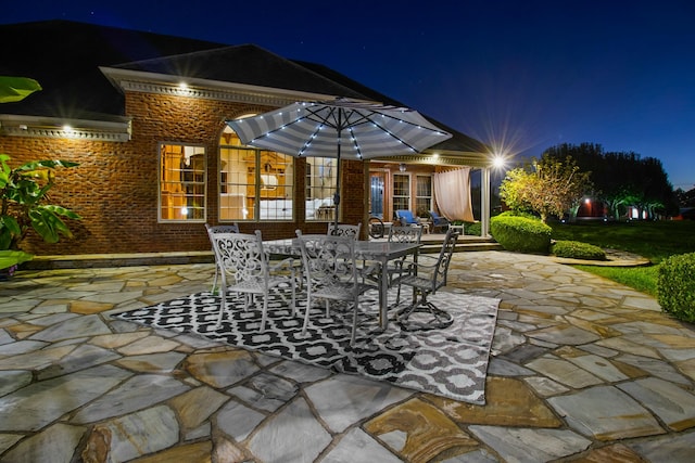 patio at night featuring outdoor dining area