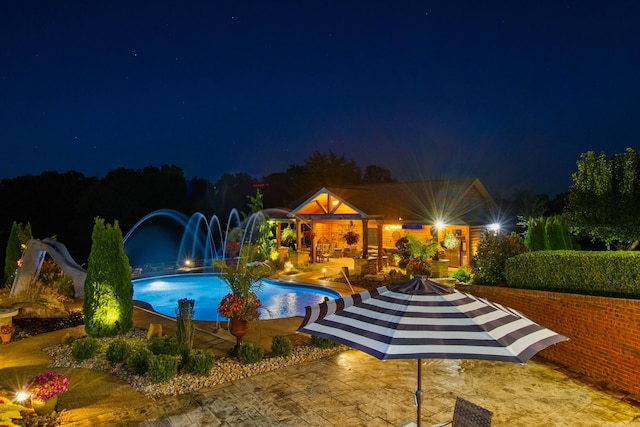 pool at night featuring a patio area and an outdoor pool