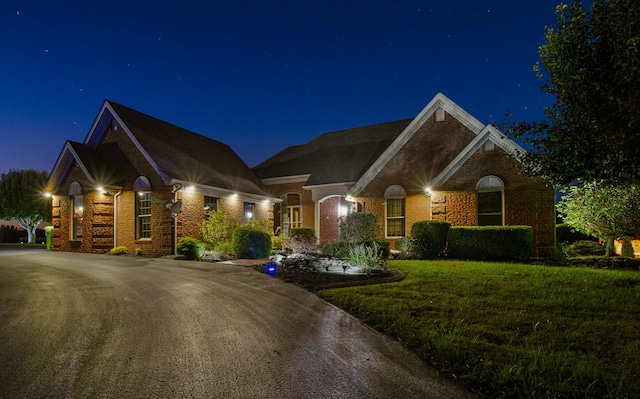 view of front of property with a yard, brick siding, and driveway