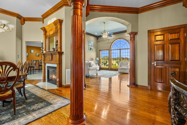 interior space with decorative columns, arched walkways, a fireplace with flush hearth, an inviting chandelier, and light wood-type flooring