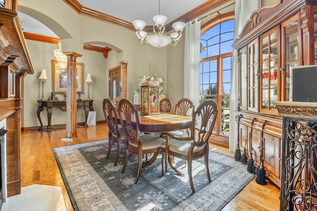 dining room with arched walkways, a notable chandelier, light wood-style flooring, ornamental molding, and baseboards