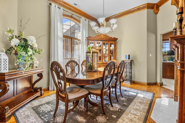 dining room with baseboards, visible vents, an inviting chandelier, crown molding, and light wood-type flooring