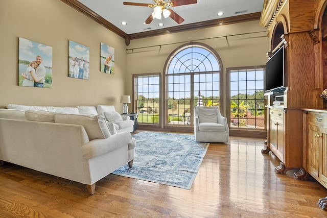 living room with ornamental molding, wood finished floors, and a healthy amount of sunlight