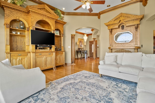 living room with arched walkways, a ceiling fan, baseboards, ornamental molding, and light wood finished floors