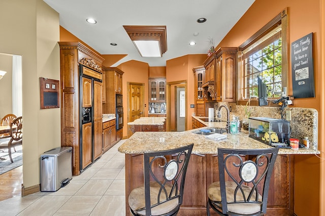 kitchen with a peninsula, a breakfast bar, brown cabinetry, and a sink