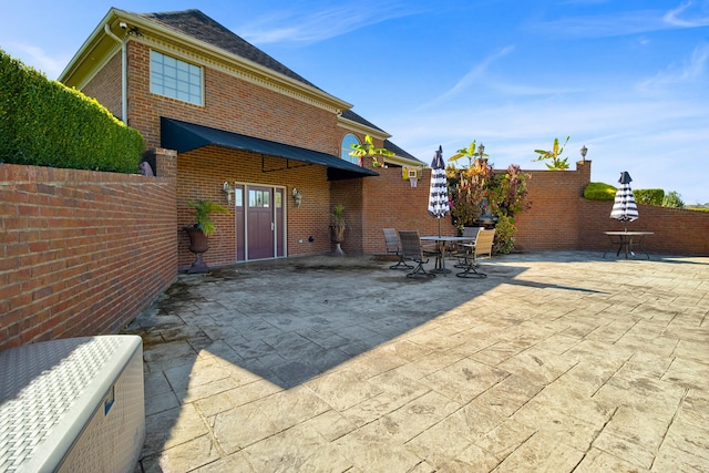 back of house featuring a patio area, fence, outdoor dining area, and brick siding