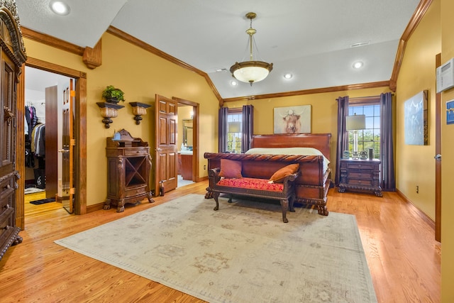 bedroom with lofted ceiling, baseboards, light wood-style floors, a walk in closet, and crown molding