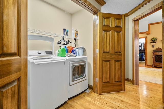 clothes washing area with laundry area, light wood-style flooring, baseboards, and independent washer and dryer